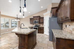 Kitchen featuring dark brown cabinets, pendant lighting, vaulted ceiling, appliances with stainless steel finishes, and light granite countertops.