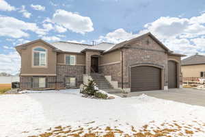 View of front of home featuring brick siding, a garage, stucco siding, and concrete driveway