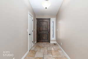 Entryway with oversized wood door and travertine tile floor.