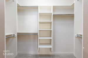 Primary walk in closet featuring light colored carpet