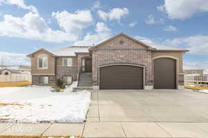 View of front of property with an attached garage, brick siding, concrete driveway, and stucco siding