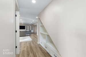 Hallway featuring recessed lighting, light wood-style flooring, and built in shelves