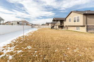 Yard covered in snow with a residential view and a fenced backyard