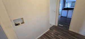 Laundry room with dark wood finished floors, hookup for a washing machine, and wooden walls