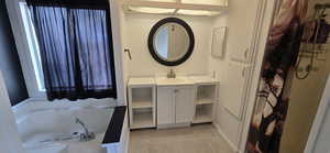 Bathroom featuring vanity, a garden tub, and a shower with shower curtain