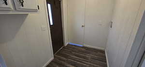 Hallway featuring dark wood-style floors and wood walls