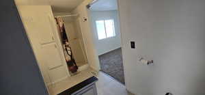 Bathroom with a stall shower, light tile patterned floors, and light carpet