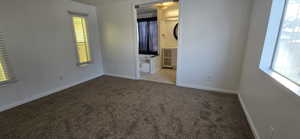 Unfurnished bedroom with multiple windows, carpet floors, and ensuite bathroom