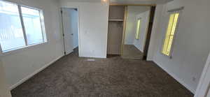 Unfurnished bedroom with dark colored carpet, a closet, and a ceiling fan