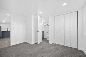 Unfurnished bedroom featuring carpet flooring, ensuite bath, recessed lighting, a closet, and freestanding refrigerator