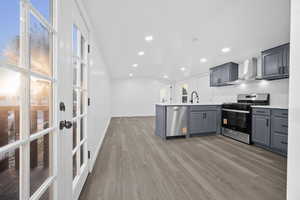 Kitchen with vaulted ceiling, stainless steel appliances, gray cabinetry, a peninsula, and light wood-style flooring