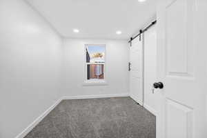 Carpeted spare room with a barn door and recessed lighting