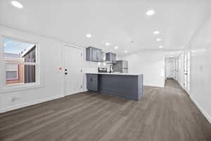 Kitchen with plenty of natural light, light countertops, a peninsula, gray cabinetry, and lofted ceiling