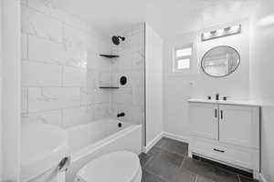 Full bathroom featuring  shower combination, vanity, a textured ceiling, and dark tile patterned flooring