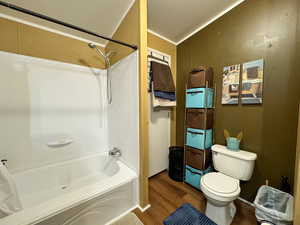 Full bath featuring shower / bathtub combination, dark wood finished floors, and ornamental molding