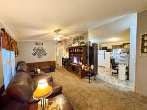Living room with an office area, ornamental molding, light colored carpet, ceiling fan, and vaulted ceiling
