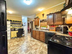 Kitchen featuring black appliances, crown molding, extractor fan, an office area, and light countertops