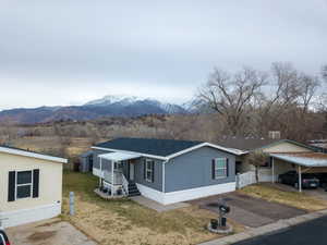 Manufactured / mobile home featuring roof with shingles, a mountain view, a front lawn, driveway, and a porch