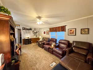 Living room featuring ornamental molding, carpet floors, and a ceiling fan