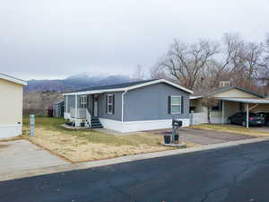Manufactured / mobile home with a mountain view, a front yard, and a carport