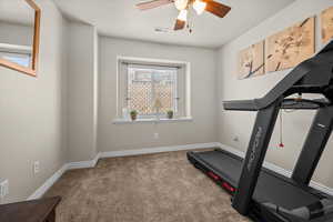 Exercise area with light colored carpet and a ceiling fan.