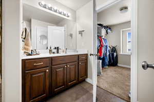 Bathroom featuring hardwood vanity, full vanity mirror, and walk-in closet.