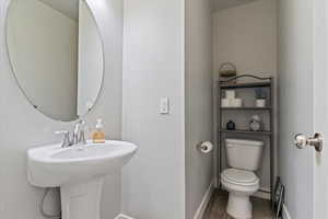 Half bathroom featuring toilet and wood finished floors