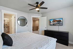 Bedroom featuring a walk in closet, light colored carpet, and a ceiling fan