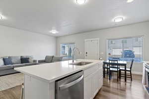 Kitchen featuring open floor plan, stainless steel appliances, dark wood finished floors, and a center island with sink