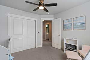 Carpeted home office featuring ceiling fan and baseboards