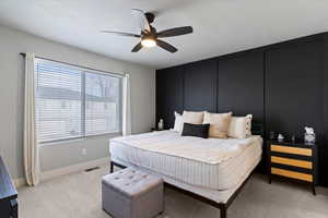 Bedroom featuring a decorative wall, light colored carpet, and a ceiling fan