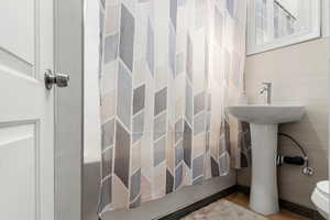 Full bathroom featuring toilet and shower / bath combination with curtain