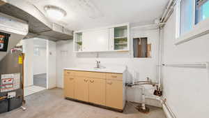 Kitchen featuring open shelves, light countertops, gas water heater, concrete floors, and healthy amount of natural light