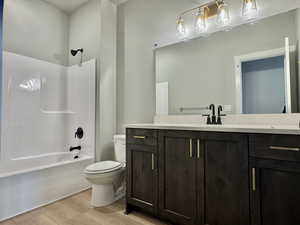 Bathroom featuring vanity, shower / bathtub combination, and light wood-style floors