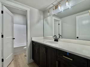 Full bath featuring vanity, a textured ceiling, light wood-style floors, and  shower combination