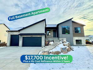 View of front of home featuring stone siding, an attached garage, and driveway