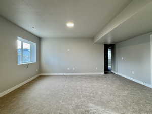 Carpeted empty room featuring baseboards and a textured ceiling