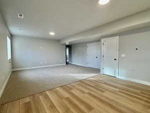 Empty room with light wood-style flooring, recessed lighting, and light colored carpet