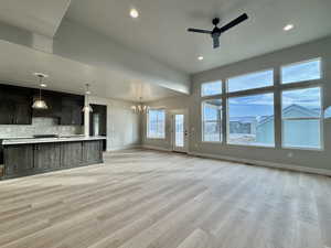 Unfurnished living room featuring a chandelier, light wood finished floors, a ceiling fan, and recessed lighting