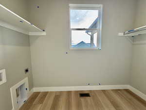 Laundry room with light wood-style flooring and hookup for an electric dryer