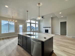 Kitchen with open floor plan, stainless steel dishwasher, a fireplace, pendant lighting, and recessed lighting