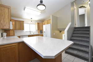 Kitchen with light countertops, white appliances, decorative backsplash, decorative light fixtures, and lofted ceiling