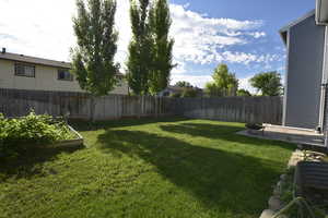 Fenced backyard with a garden and a patio area