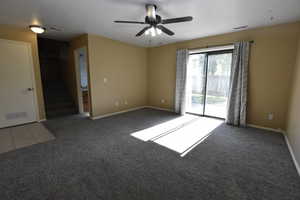 Carpeted spare room with stairs and a ceiling fan