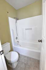 Full bathroom with light tile patterned floors and shower / tub combination