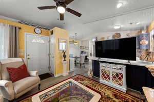 Living room with a ceiling fan, wood finished floors, and lofted ceiling