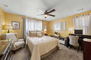 Bedroom with carpet, a textured ceiling, a ceiling fan, and a desk