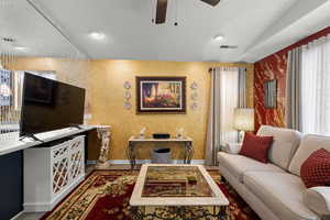 Living area with wallpapered walls, a ceiling fan, and a textured ceiling