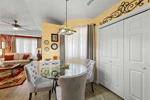Dining area with light wood-style flooring, ceiling fan, and vaulted ceiling