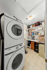 Laundry area featuring stacked washer / drying machine, light flooring, and a textured ceiling